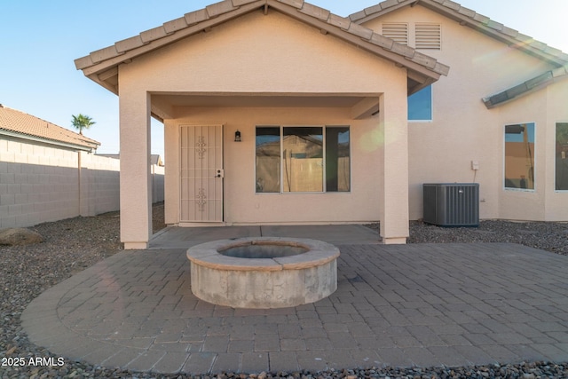 rear view of house with central AC unit, a patio area, and a fire pit