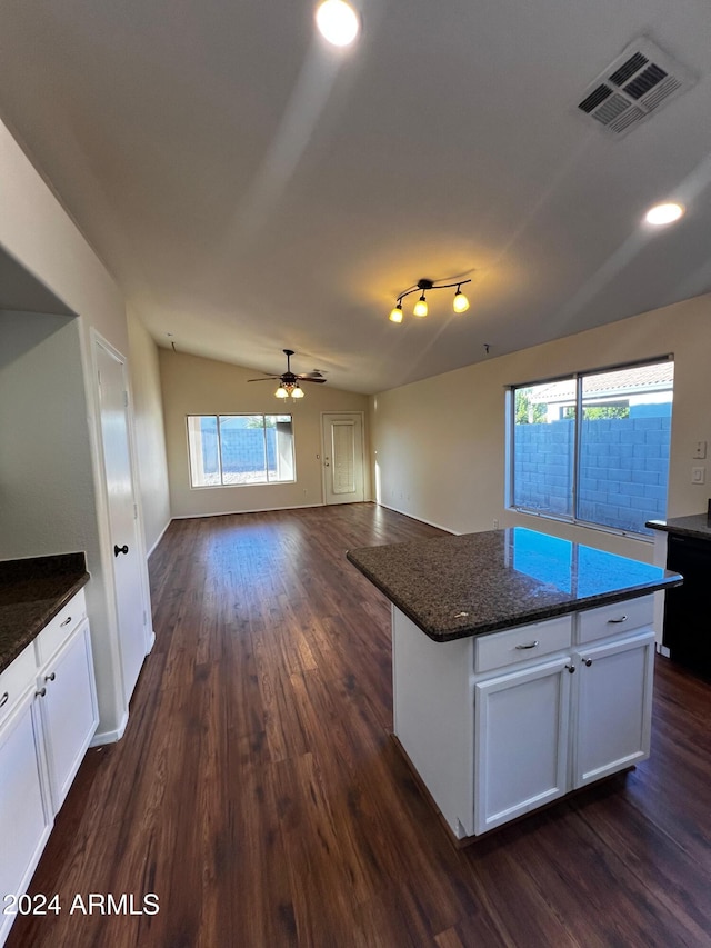 kitchen featuring lofted ceiling, dishwasher, white cabinets, a kitchen island, and dark stone counters