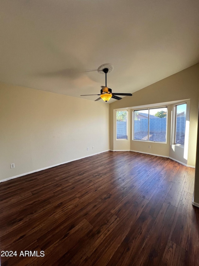 empty room with ceiling fan, lofted ceiling, and dark hardwood / wood-style flooring