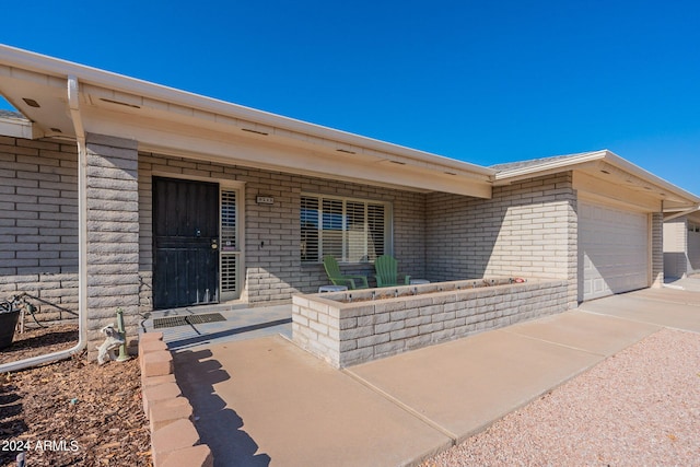 property entrance featuring a garage, brick siding, and a porch