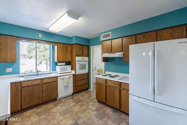 kitchen featuring light countertops, visible vents, a sink, white appliances, and under cabinet range hood