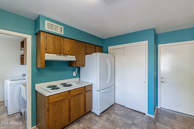 kitchen featuring under cabinet range hood, white appliances, visible vents, stone finish floor, and brown cabinetry