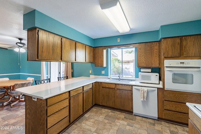 kitchen featuring white appliances, light countertops, a sink, and stone finish flooring