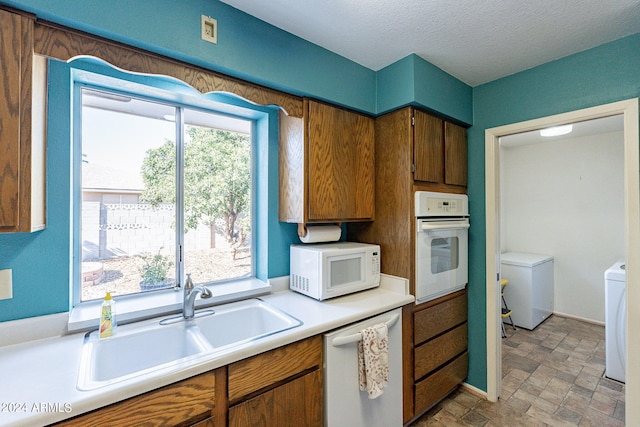 kitchen with a wealth of natural light, white appliances, light countertops, and washer and clothes dryer