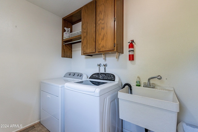 laundry area featuring cabinet space, baseboards, washer and clothes dryer, and a sink