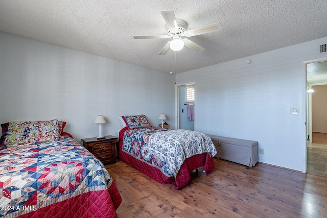 bedroom with a textured ceiling, hardwood / wood-style flooring, and a ceiling fan