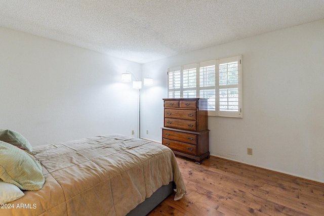 bedroom with a textured ceiling and wood finished floors