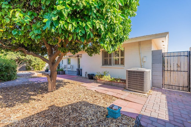 exterior space featuring brick siding, a patio, a gate, central AC, and ceiling fan