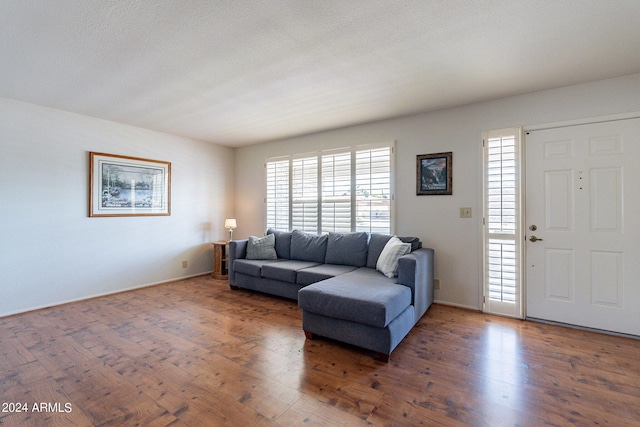 living area featuring a textured ceiling, baseboards, and wood finished floors