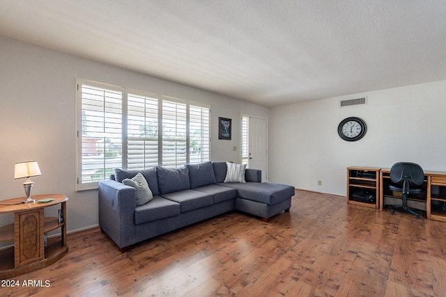 living room with a textured ceiling, visible vents, and wood finished floors