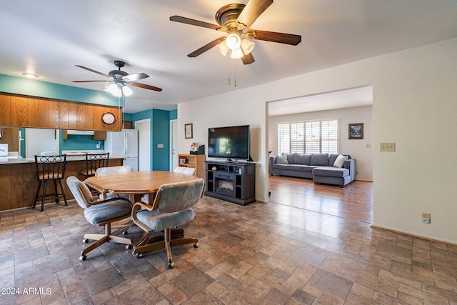 dining space with stone finish floor, a ceiling fan, and baseboards