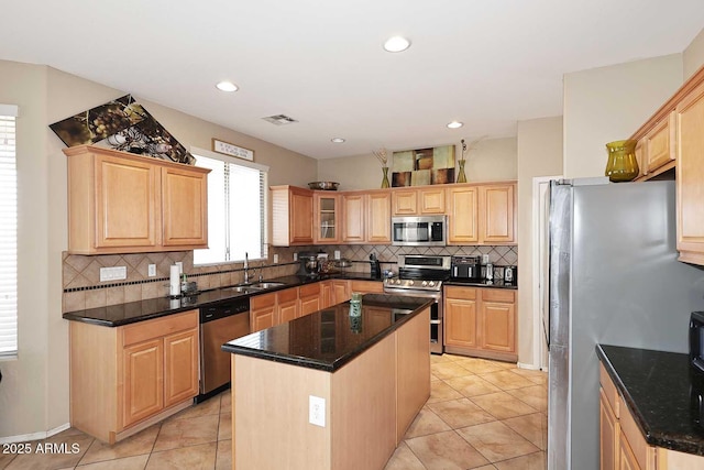 kitchen with a kitchen island, a sink, visible vents, appliances with stainless steel finishes, and light brown cabinetry