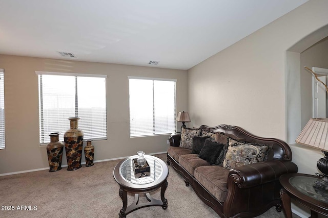 carpeted living room with arched walkways, lofted ceiling, visible vents, and baseboards