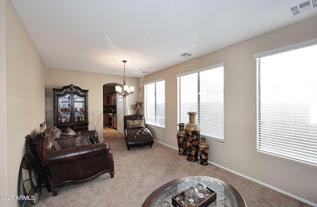 carpeted living room featuring arched walkways, a chandelier, visible vents, and baseboards