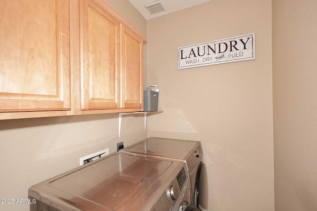 washroom with visible vents, cabinet space, and washer and dryer