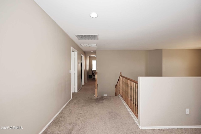 corridor with arched walkways, carpet floors, an upstairs landing, and visible vents