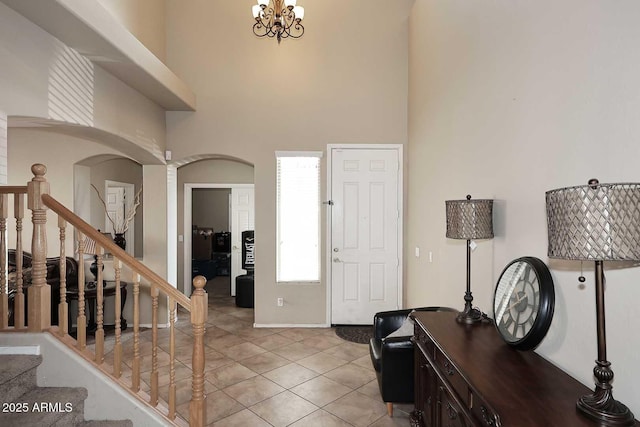 entrance foyer featuring a chandelier, stairway, light tile patterned flooring, and a towering ceiling