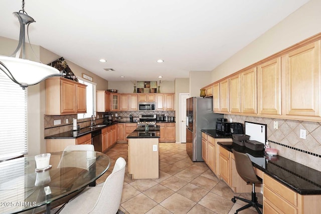 kitchen with light brown cabinets, stainless steel appliances, a sink, and a center island