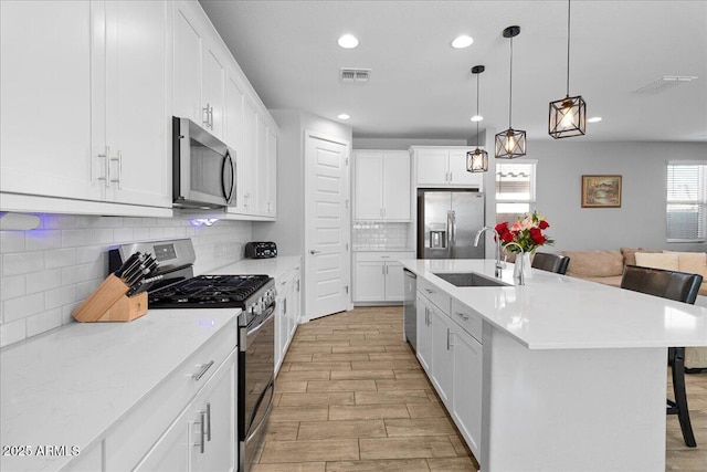 19447 W Mariposa Dr, Litchfield Park, AZ 85340 - kitchen with appliances with stainless steel finishes, a sink, a kitchen breakfast bar, light wood-style flooring, and backsplash