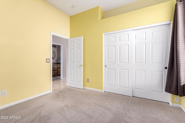 unfurnished bedroom featuring light carpet and a closet