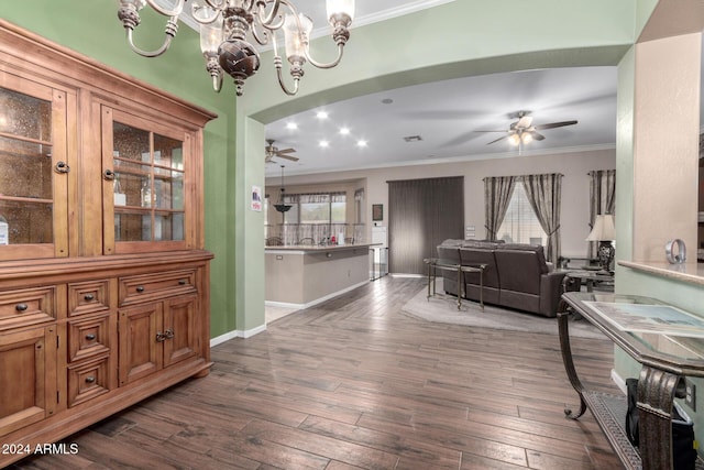 dining space featuring crown molding, dark wood-type flooring, and ceiling fan with notable chandelier