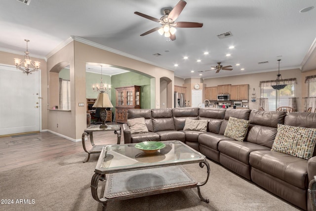 living room with ceiling fan with notable chandelier, light wood-type flooring, and crown molding