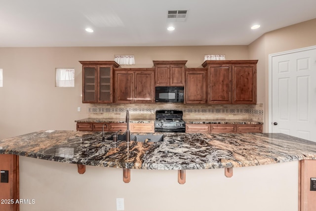 1260 E Sweet Citrus Dr, Queen Creek, AZ 85140 - kitchen with gas range, black microwave, a sink, tasteful backsplash, and a breakfast bar