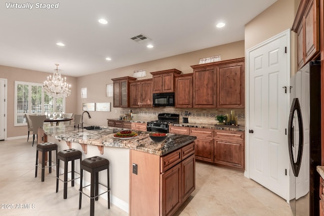 1260 E Sweet Citrus Dr, Queen Creek, AZ 85140 - kitchen featuring black appliances, a sink, a kitchen bar, tasteful backsplash, and a large island with sink