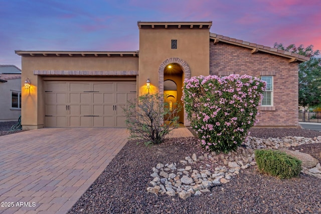 1260 E Sweet Citrus Dr, Queen Creek, AZ 85140 - mediterranean / spanish-style house with brick siding, decorative driveway, an attached garage, and stucco siding