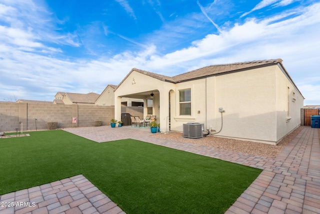 back of house featuring central AC, ceiling fan, a patio area, and a lawn