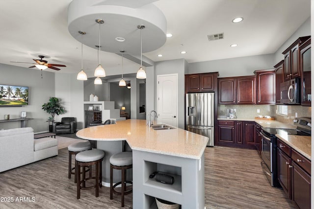 13072 W Alyssa Ln, Peoria, AZ 85383 - kitchen with appliances with stainless steel finishes, a sink, open floor plan, a kitchen bar, and dark wood-type flooring