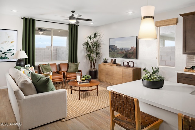 living room featuring ceiling fan, plenty of natural light, and light hardwood / wood-style floors