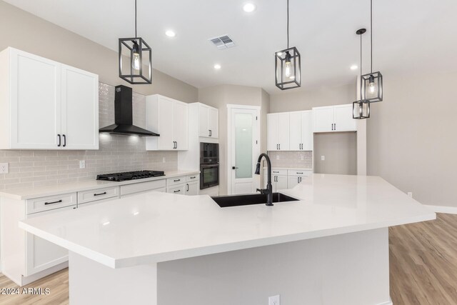 kitchen with a large island, light hardwood / wood-style floors, sink, white cabinetry, and wall chimney exhaust hood