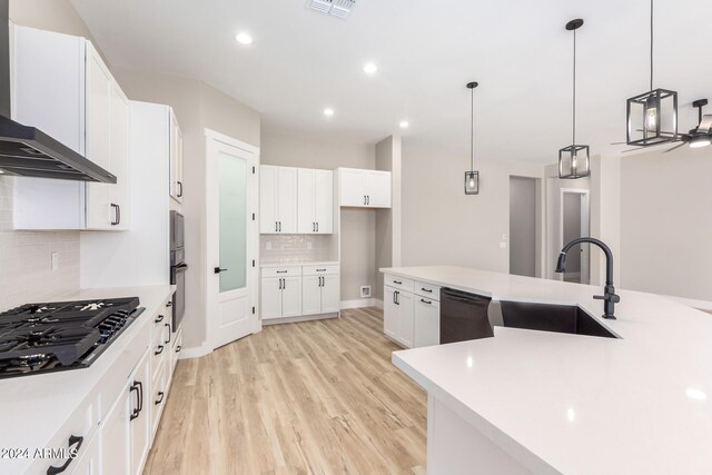 kitchen featuring light hardwood / wood-style floors, sink, white cabinets, wall chimney exhaust hood, and black appliances