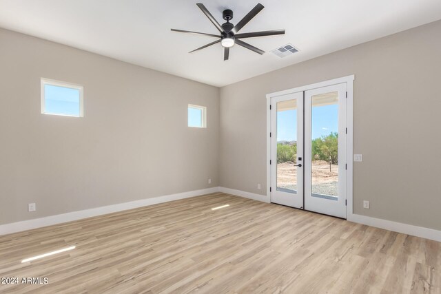 empty room with light hardwood / wood-style floors, ceiling fan, plenty of natural light, and french doors