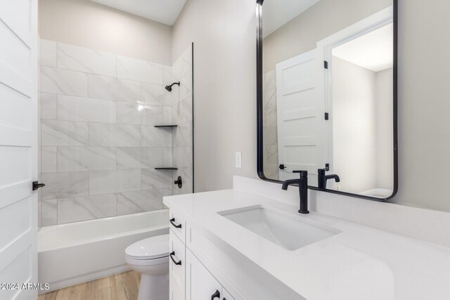 full bathroom with tiled shower / bath, vanity, toilet, and hardwood / wood-style flooring