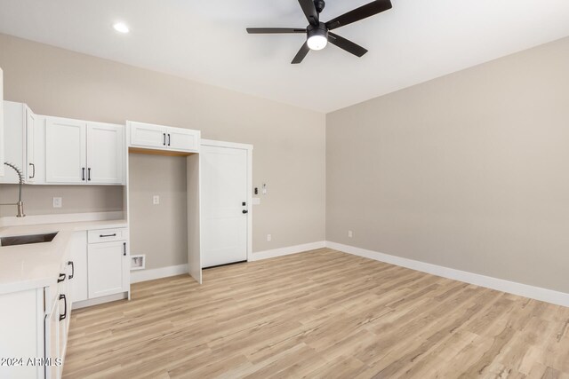 kitchen featuring light wood-type flooring, white cabinetry, ceiling fan, and sink