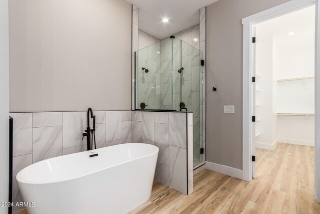 bathroom featuring hardwood / wood-style flooring, plus walk in shower, and tile walls