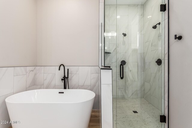 bathroom featuring independent shower and bath and tile walls