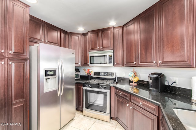 kitchen featuring dark stone countertops, light tile patterned floors, and stainless steel appliances