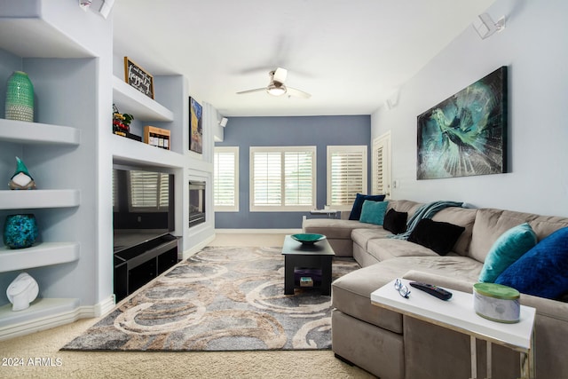 living room featuring built in shelves, ceiling fan, and light carpet