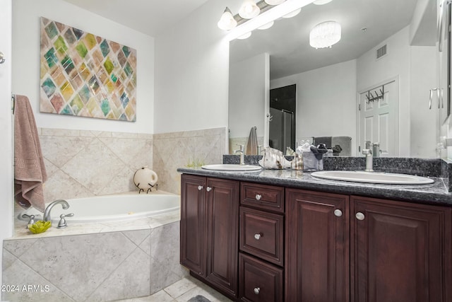 bathroom featuring tiled tub, vanity, and tile patterned flooring