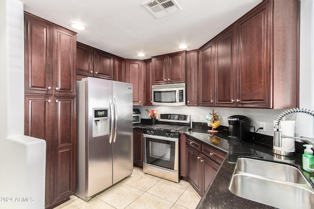 kitchen featuring light tile patterned flooring, appliances with stainless steel finishes, sink, and dark stone countertops