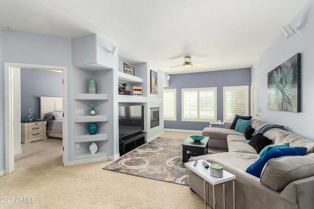 living room featuring ceiling fan, light colored carpet, and built in features