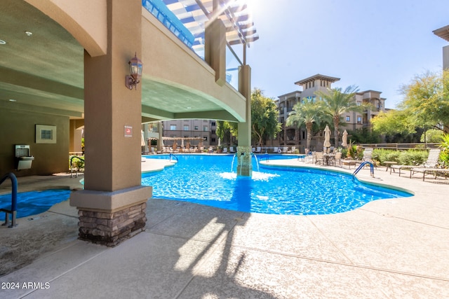 view of swimming pool with pool water feature and a patio