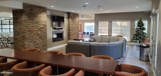 living room with a stone fireplace and light hardwood / wood-style flooring