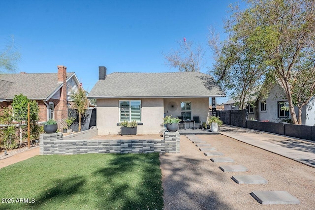 bungalow-style home with a patio, stucco siding, a shingled roof, fence, and a front lawn