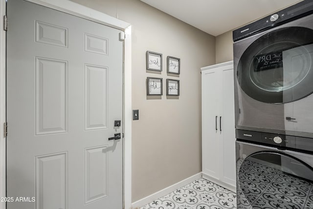 laundry area featuring stacked washer and clothes dryer, cabinet space, baseboards, and light tile patterned floors