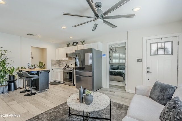 living area with recessed lighting, visible vents, ceiling fan, and light wood finished floors