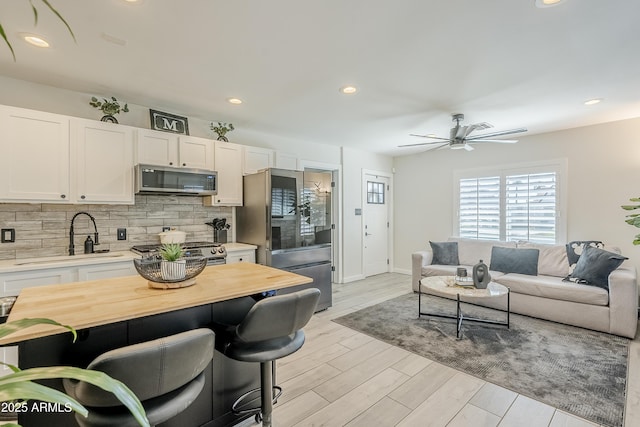 kitchen with tasteful backsplash, light wood-style flooring, appliances with stainless steel finishes, white cabinetry, and a sink